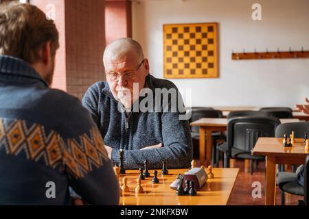 Men playing chess at table in country club Stock Photo