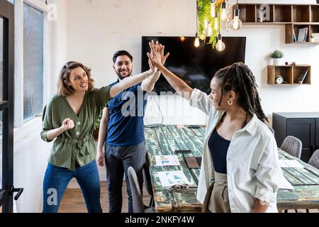 Happy businesswoman with colleagues doing high five in office Stock Photo