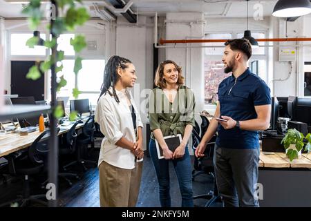 Young businessman discussing with coworkers in office Stock Photo