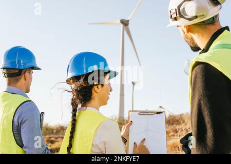 Engineers discussing with technician over wind turbine diagram Stock Photo
