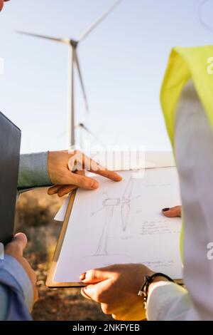 Engineers discussing over wind turbine diagram Stock Photo