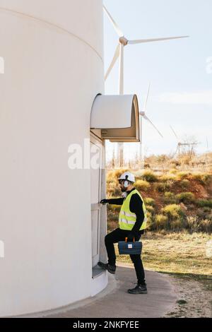 Technician with toolbox entering wind turbines Stock Photo