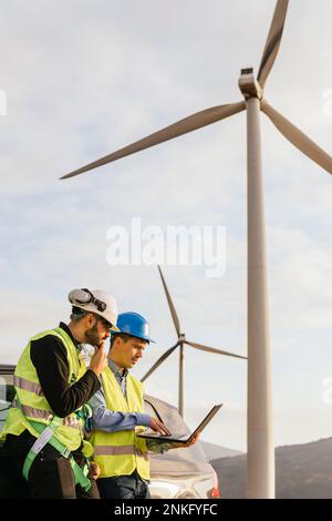 Technician and engineer working on laptop standing by car Stock Photo