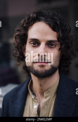 Confident young businessman with curly hair Stock Photo