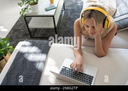 Freelancer wearing wireless headphones using laptop at home Stock Photo