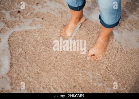 Woman standing on wet sand at beach Stock Photo