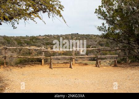 Wooden Park benches on a scenic overlook pond in Pedernales Falls State Park as part of the Texas Hill Country. Stock Photo