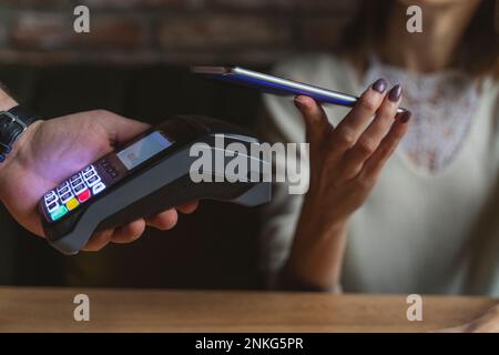 Woman making payment through mobile phone at cafe Stock Photo