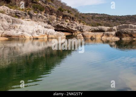A wall of geological limestone formations creates a canyon and cliff overhang near the river in Pedernales Falls State Park as part of the Texas Hill Stock Photo