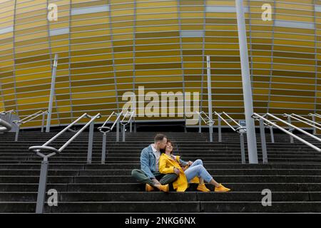 Man kissing woman on staircase outside stadium Stock Photo
