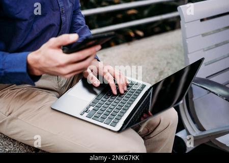 Businessman with smart phone using laptop Stock Photo