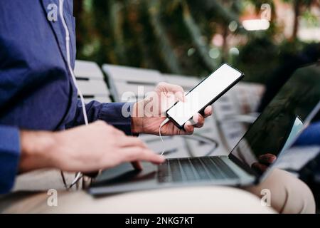 Young businessman with smart phone using laptop Stock Photo
