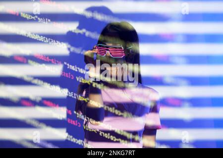 Young woman with futuristic eyewear reading codes over colored background Stock Photo