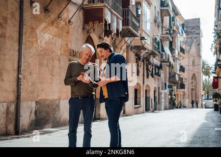 Father and son using smart phone standing on street Stock Photo