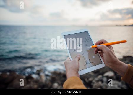Hands of senior man drawing wind turbine on tablet PC with digitized pen Stock Photo
