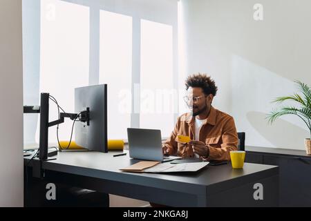 Smiling businessman using laptop and making payment with credit card Stock Photo