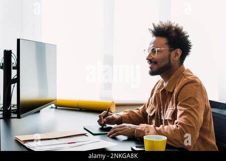 Smiling businessman working on desktop PC at office Stock Photo