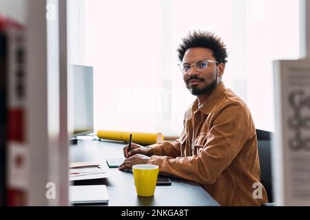 Businessman using graphics tablet sitting at desk Stock Photo