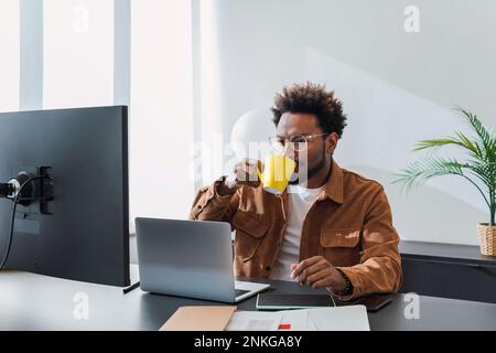 Businessman drinking coffee and working in office Stock Photo