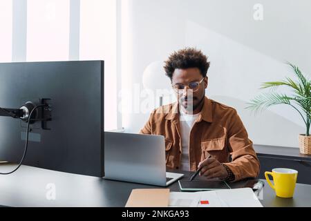 Businessman with laptop using graphics tablet in office Stock Photo