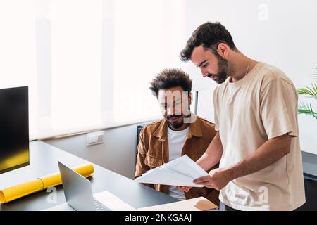 Businessman discussing over documents with colleague at office Stock Photo