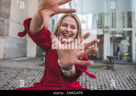Cheerful mature woman making finger frame in front of building Stock Photo