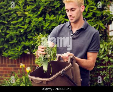 Young man recycling food waste in back yard Stock Photo