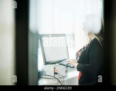 Woman typing on keyboard at screen in modern factory Stock Photo