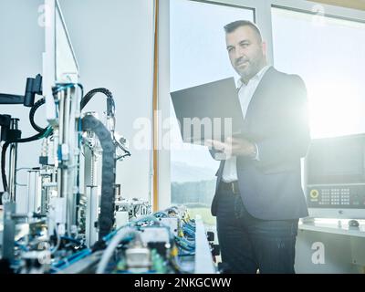 Businessman using laptop in modern factory Stock Photo
