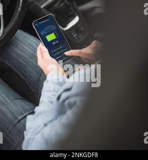 Hand of woman operating electric car through mobile app on smart phone Stock Photo