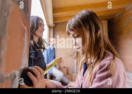 Happy family measuring window together at home Stock Photo
