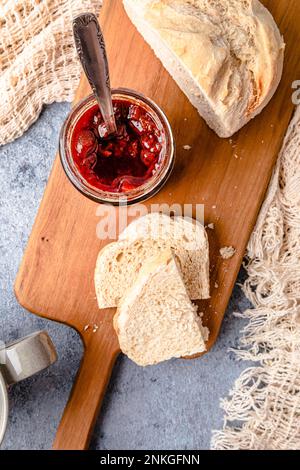 Homemade strawberry jam with bread on cutting board Stock Photo