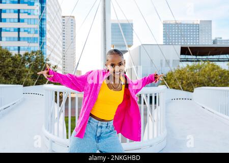 Smiling young woman dancing on footbridge Stock Photo