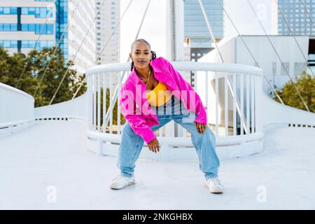 Confident young dancer breakdancing on footbridge Stock Photo