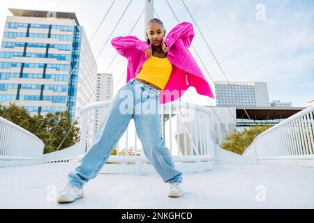 Confident young dancer breakdancing on footbridge Stock Photo