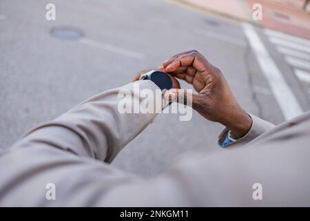 Businessman checking time on smart watch at road Stock Photo