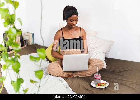 Smiling pregnant freelancer using laptop at home Stock Photo