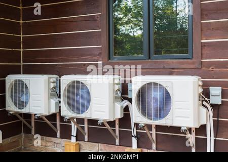 Air conditioning units mounted on outside wall of brown stained milled Eastern white pine timber and flat log profile home. Stock Photo