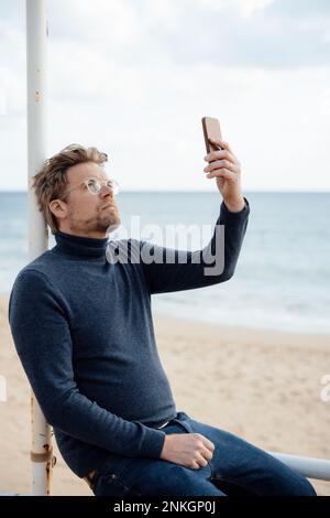 Man using mobile phone at beach Stock Photo