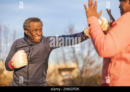 Senior man practicing boxing with woman in park Stock Photo
