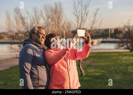 Happy senior couple taking selfie through smart phone at park Stock Photo