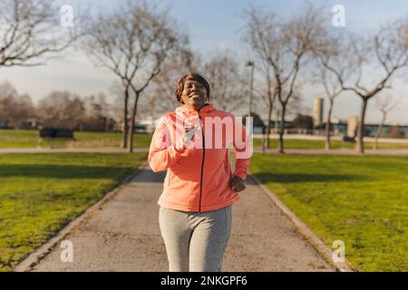 Happy senior woman running at park Stock Photo