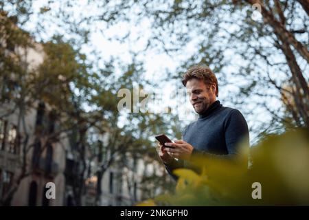 Smiling man using mobile phone Stock Photo