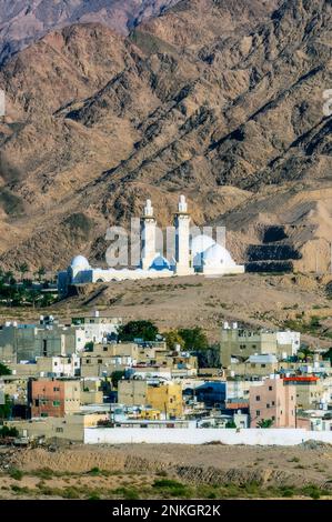 Sheikh Zayed Mosque near buildings in front of mountains on sunny day Stock Photo