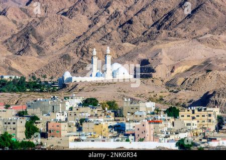 Sheikh Zayed Mosque and buildings in front of mountains on sunny day Stock Photo