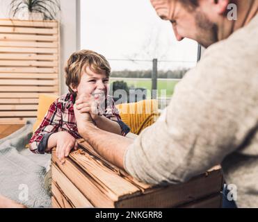 Father with son doing arm wrestling at home Stock Photo