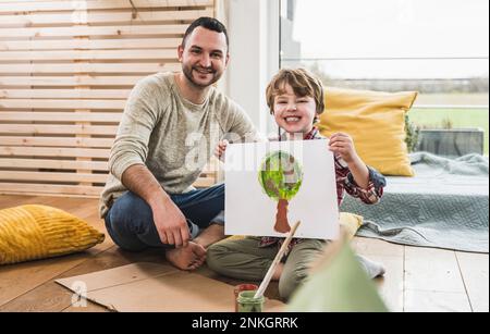Happy father with son showing tree painting at home Stock Photo