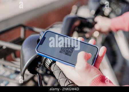 Man paying with smart phone at electric bicycle sharing system Stock Photo