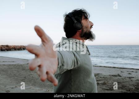 Happy man with arms outstretched enjoying at beach Stock Photo