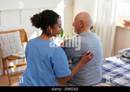 Doctor using stethoscope examining patient at home Stock Photo